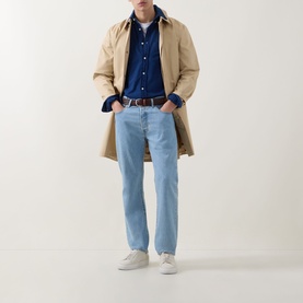 Model wearing Gant Dark Indigo Reg Shirt styled with beige trench coat, light wash jeans, brown belt and white trainers.
