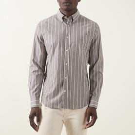Model wearing Gant Logo Striped Shirt in brown melange, long sleeves, button-down collar, chest pocket, styled with cream trousers.