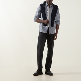 Model wearing Gant Logo Striped Shirt in Dark Indigo Melange with navy knit vest, dark trousers and black leather shoes.