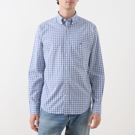 Model wearing Gant Classic Check Logo Shirt in Fresh Blue check, paired with light wash jeans. Button-down collar, chest pocket, long sleeves.