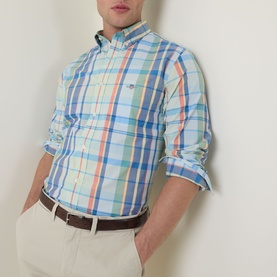 Model wearing Gant Shield Logo Checked Casual Shirt in Misty Mint plaid, long sleeves rolled up, paired with white chinos and brown belt.