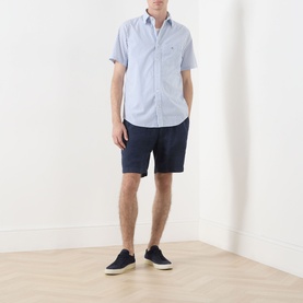 Model wearing Gant Fresh Blue regular fit short-sleeve cotton shirt, styled with navy shorts and dark canvas shoes.