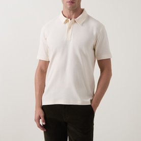 Model wearing Gant Cream Regular Polo in 100% cotton, styled with dark olive trousers.
