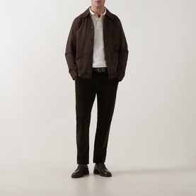 Model wearing Gant Regular Polo in cream, styled with dark brown jacket, olive trousers, and leather derby shoes.