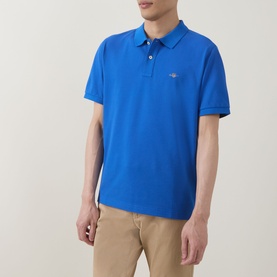 Model wearing Gant Regular Polo in Nautical Blue, short sleeves, embroidered logo, styled with beige chinos.