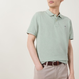 Model wearing Gant Regular Polo in soft green melange, short sleeves, styled with beige chinos and brown belt.