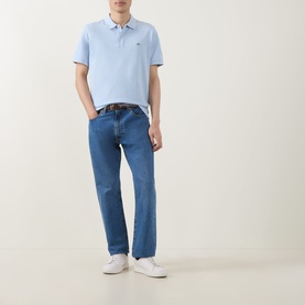 Model wearing Gant Fresh Blue Regular Polo with blue jeans, brown belt and white trainers.
