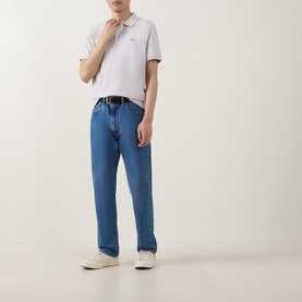 Model wearing Gant Shield Logo Pique Polo Shirt in Glacier Melange with blue straight-leg jeans and white trainers.