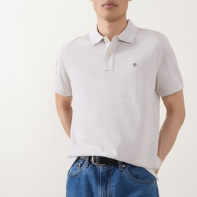 Model wearing Gant Shield Logo Pique Polo Shirt in Glacier Melange, short sleeves, embroidered shield logo, styled with blue jeans.