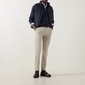 Model wearing Gant Evening Blue sweatshirt, layered under a navy quilted jacket, styled with beige trousers and dark brown boots.
