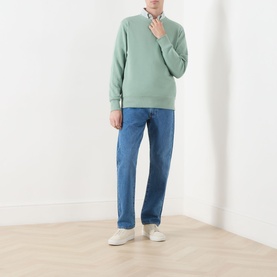Model wearing Gant Shield Logo Sweatshirt in Surplus Mint with blue jeans and white trainers.