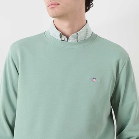 Model wearing Gant Shield Logo Sweatshirt in Surplus Mint, crew neck with embroidered shield logo, styled over a checked collar shirt.