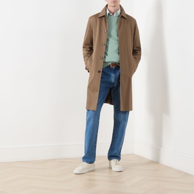 Model wearing Gant Shield Logo Sweatshirt in Surplus Mint with camel mac coat, blue jeans, and white trainers.