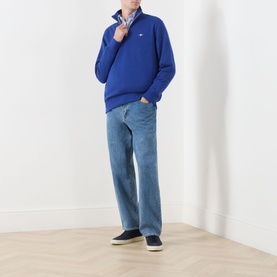 Model wearing Gant Crisp Blue quarter-zip sweatshirt with light blue jeans and dark navy trainers.