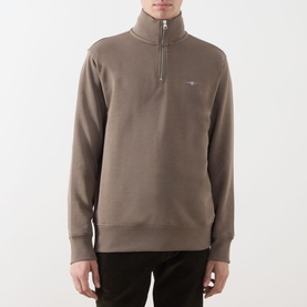 Model wearing Gant Faded Taupe half-zip sweatshirt with small logo embroidery, styled with dark trousers.