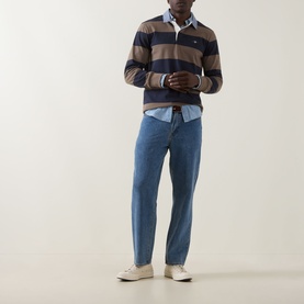 Model wearing Gant Stripe Heavy Rugger Shirt in Faded Taupe, navy stripe, with light blue shirt and mid-wash jeans.