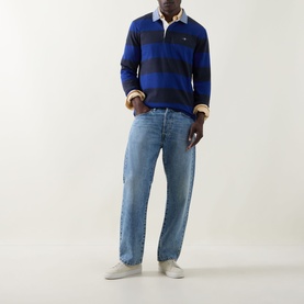 Model wearing Gant Shield Logo Striped Rugby Shirt in crisp blue, styled with light wash jeans and white trainers.