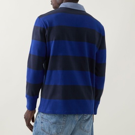 Model wearing Gant Shield Logo Striped Rugby Shirt in Crisp Blue, back view showing navy block stripes, contrast collar, and ribbed cuffs, styled