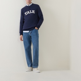 Model wearing Gant V-Stitch Logo Sweatshirt in navy with white Yale graphic, styled with light blue jeans and white trainers.