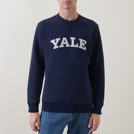 Model wearing Gant V-Stitch Logo Sweatshirt in navy with white Yale graphic, ribbed trims and straight hemline, styled with blue jeans.