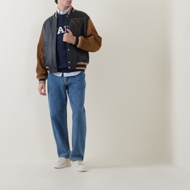 Model wearing Gant V-Stitch Logo Sweatshirt in navy, styled with a varsity jacket, blue jeans and white trainers.
