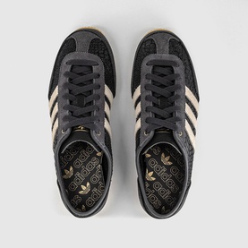 Adidas trainers in utility black with cream white stripes, black laces, gold branded insole, and gum sole, overhead view.