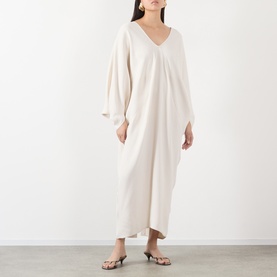 Model wearing The Frankie Shop Ivory Dress in viscose, featuring V-neck, voluminous sleeves and maxi length, styled with strappy sandals.