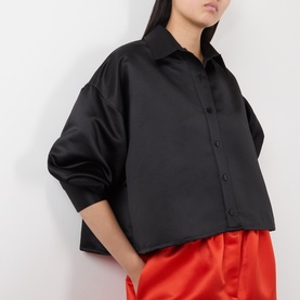 Model wearing The Frankie Shop black oversized cropped shirt in polyester, styled with red wide-leg trousers