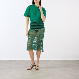 Model wearing The Frankie Shop green leather crochet mesh midi skirt with fringe hem, styled with a green top and black strappy heels