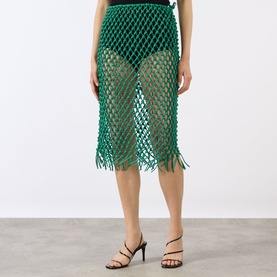 Model wearing The Frankie Shop green leather macram&eacute; net midi skirt with fringe hem, styled with black strappy heeled sandals