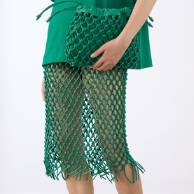 Model wearing The Frankie Shop green leather macram&eacute; net midi skirt with fringe hem, styled with a green top.