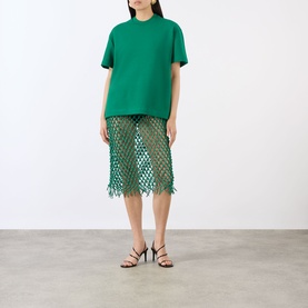 Model wearing The Frankie Shop emerald cotton T-shirt, styled with matching green crochet midi skirt and black strappy heels.