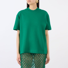 Model wearing The Frankie Shop emerald green cotton T-shirt with mock neck, styled with sheer green mesh skirt.