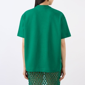 Model wearing The Frankie Shop emerald green oversized cotton T-shirt, back view, styled with green crochet trousers.