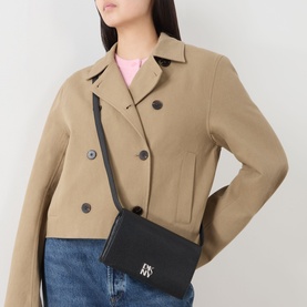 Model carrying DKNY Etta Wallet Crossbody Bag in black with silver-tone logo hardware and adjustable strap, styled with a camel cropped jacket.