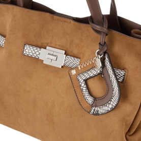 DKNY almond faux suede satchel, close-up of silver-tone buckle detail and snake-effect charm accent with brown leather trim