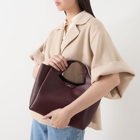 Model carrying DKNY Willa Logo Satchel in Aged Wine, faux grained leather tote with silver-toned hardware, styled with cream oversized jacket