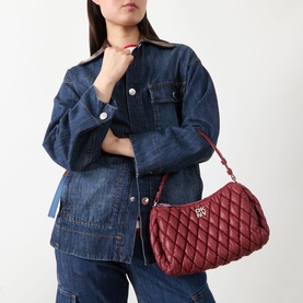 Model carrying DKNY Remy Quilted Shoulder Bag in Rhythm Red with silver-tone hardware, styled with a denim jacket and jeans.