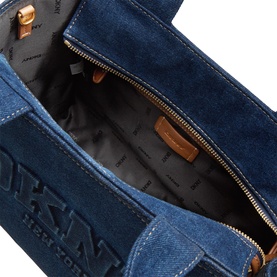 DKNY dark denim tote bag, open top view showing fabric interior lining, gold-tone zip and embossed logo detail on front panel