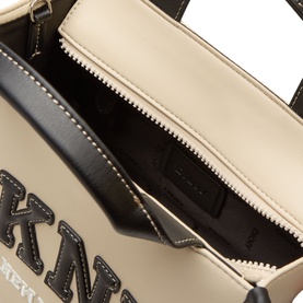 DKNY Hadlee Small Tote Bag in light taupe, showing open interior with zip pocket, black lining, and contrast stitching detail