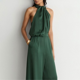 Model wearing Reiss teal green halterneck jumpsuit with wide-leg silhouette and gathered neckline, styled with gold cuff bracelet