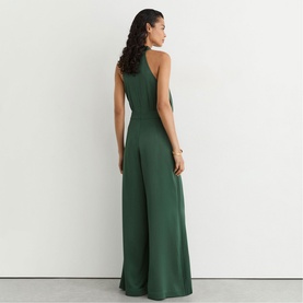 Model wearing Reiss teal green wide-leg halterneck jumpsuit, back view, styled with a gold bracelet.