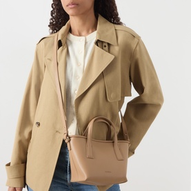 Model carrying Marella Sesamo Logo Tote Bag in camel with gold-tone hardware and top handles, styled with a beige trench coat.