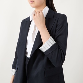Model wearing Marella navy plain wool blazer with rolled sleeves, styled with a white striped shirt, cropped torso view.