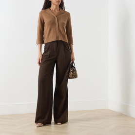 Model wearing Marella Alpaca Knitted Polo Cardigan in camel with wide-leg brown trousers, carrying a zebra-print bag.