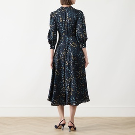 Model wearing Marella Navy Pebbles dress, back view, 3/4 sleeves, floral print, midi length, styled with black heeled sandals.