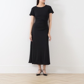 Model wearing Marella black short-sleeve midi dress with ruched waist detail and flared skirt, styled with black strappy heels.