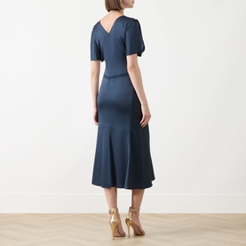 Model wearing Marella Aviation blue midi dress, back view, short puff sleeves, flared hem, styled with gold heeled sandals
