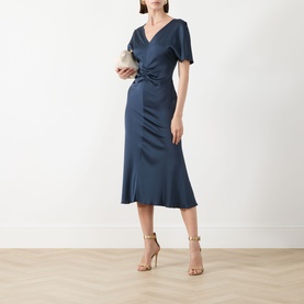 Model wearing Marella aviation blue midi dress with ruched waist detail and flutter sleeves, styled with gold heeled sandals and clutch bag