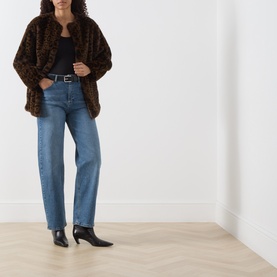 Model wearing Marella Cocoa Spotted faux fur jacket, styled with blue straight-leg jeans, black top, belt and heeled ankle boots.